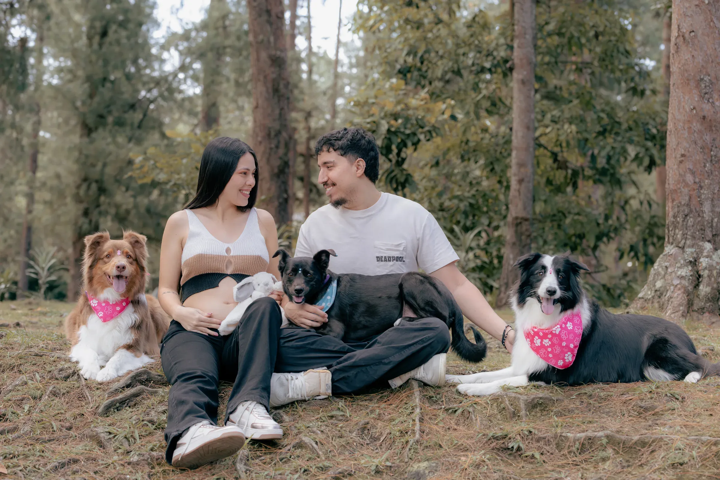 Santiago and Alejandra sitting in the forest with the family dogs around Aarón.