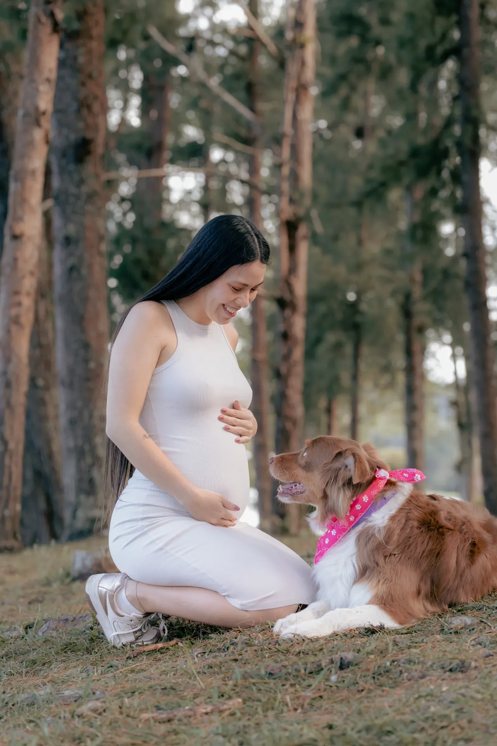 Alejandra smiling at one of the family dogs while holding Aarón close.