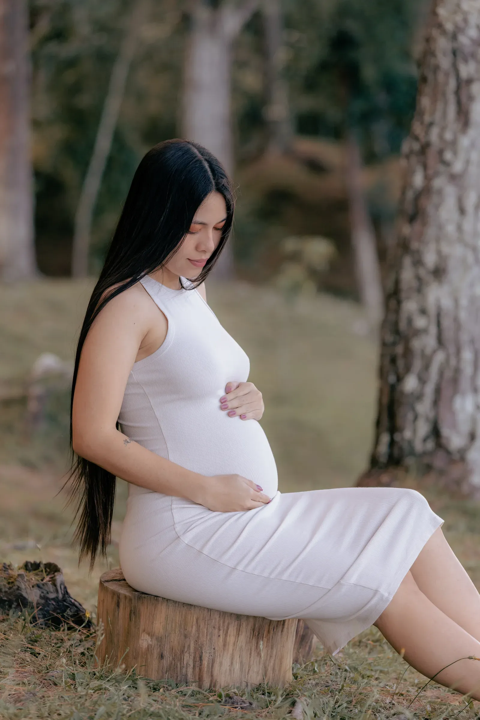 Alejandra sitting peacefully on a tree stump with both hands around Aarón.